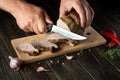 Chef slicing grilled beef meat on a cutting board. Work environment on the kitchen table with condiments or spices. Black or dark Royalty Free Stock Photo