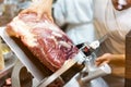 A chef is slicing a raw beef by meat slicer.