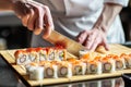 chef slicing sushi rolls on a bamboo mat