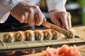 chef slicing sushi rolls on a bamboo mat