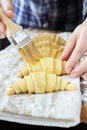 Chef smearing raw croissants with brush in yolk Royalty Free Stock Photo