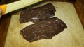 Chef softens raw beef liver and often beats it with a knife, on wooden cutting board.