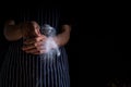 Chef sprinkle icing sugar on the donut. Male baker sprinkles sweet donuts with powder and icing sugar on black background. Space