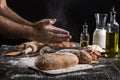 Chef sprinkles fresh bread with flour. Man preparing dough at table in kitchen. Royalty Free Stock Photo