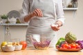 Chef sprinkles salt on salad, stir, in the process of a vegetarian salad with the hand of the chef in the home kitchen.Healthy