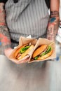 Chef with tattoos on his hands holds two burgers Royalty Free Stock Photo
