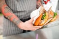 Chef with tattoos on his hands holds two burgers Royalty Free Stock Photo