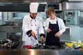 Chef teacher teaches cooking to the group children in class kitchen room.