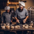 Chef teaching his assistant to bake the bread in a bakery.