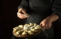 The chef throws flour to raw dumplings on a cutting kitchen board before cooking. Black space for menu or recipe Royalty Free Stock Photo