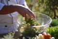 chef tossing salad in a bowl outside