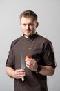 A chef in a uniform jacket shows off a professional chef`s knife and a tomato