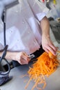 Chef in uniform preparing fresh carrot batons