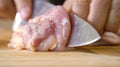 A chef using a kitchen knife slices uncooked chicken meat on a chopping board, the close up view of preparing food ingredients Royalty Free Stock Photo
