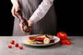 Chef using pepper mill. grilled vegetables and fish. pepper. female hands of the chef. on a black background Royalty Free Stock Photo