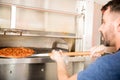 Chef using special shovel to removing hot pizza from modern oven