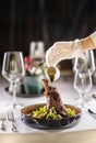 The chef or waiter finishes the meal right on the restaurant table, pouring the sauce over the leg of lamb confit