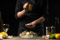 Chef watering raw oyster with lemon juice, with dry Italian wine, for cooking and cooking on a black background, Concept menu,