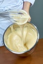 Chef whips yellow cream in a bowl by hand for making cheesecakes