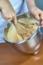 Chef whips yellow cream in a bowl by hand for making cheesecakes