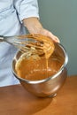 Chef whips yellow cream in a bowl by hand for making cheesecakes