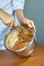 Chef whips yellow cream in a bowl by hand for making cheesecakes