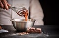 Chef whisking melted chocolate in a mixing bowl