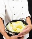 Chef in white jacket holding around a casserole