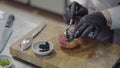 Chef in white restaurant uniform decorating a plate with tuna fish and selmon and put inside a black caviar. Slow motion