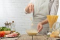 Chef in white uniform pours cheese in sauce into glass bowl for cooking pasta alla carbonara. Backstage of preparing traditional Royalty Free Stock Photo