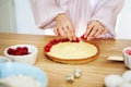 Chef Woman decorating cake with berries and cream cheese on kitchen table. Close-up of female hands cooking tartlet with