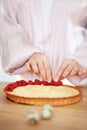 Chef Woman decorating cake with berries and cream cheese on kitchen table. Close-up of female hands making tartlet with Royalty Free Stock Photo