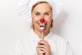 Chef woman holdinh a fork with tomato against her nose, standing