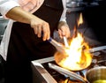 Chef cooking with flame in a frying pan on a kitchen stove Royalty Free Stock Photo
