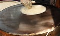 Chef's hand making roti in a hot iron pan.