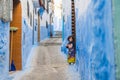 Chefchaouen, Morocco - APRIL 30 2019: View of a narrow blue street with a small moroccan child