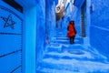 Asian woman tourist in red dress walking on a street in Medina of Chefchaouen