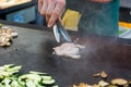 Cheff preparing traditional Mediterranean squid dish on a hot grill.