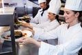 Chefs handing dinner plates through order station Royalty Free Stock Photo