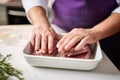 chefs hands layering eggplant for moussaka in a baking pan