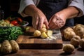 chefs hands peeling and slicing potatoes on a wooden surface