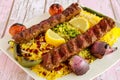 Chelo Kabab Rice topping with pistachio, onion, tomato, lemon slice and pomegranate seeds served in dish isolated on table closeup