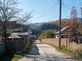 Chemal, Altai Republic, Russia - 10 October 2020: Village road along wooden houses and and fence. Autumn view against the backdrop Royalty Free Stock Photo