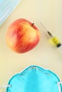 Chemical additives in food or genetically modified fruit concept. Red apple with syringes of chemicals. Isolated on red backgroun