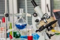 Chemical distillation glasses with microscopes placed in a laboratory with red, orange, blue chemicals in the beaker and tubes