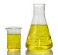 A chemical flask, a beaker with yellow liquids and a sheet of pa