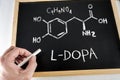 Chemical Formula and nomenclature of L-DOPA handwritten with chalk on a blackboard