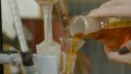 Chemical glass with green fluid poured into a red one among the funnels. Hand adds red mixed liquid in flask. a chemist