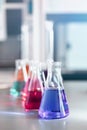 Chemical laboratory flask with blue purple-pink liquid stand on the table Royalty Free Stock Photo