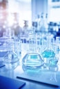 Chemical laboratory, glassware with blue liquid on glossy table surface, vertical image, selective focus